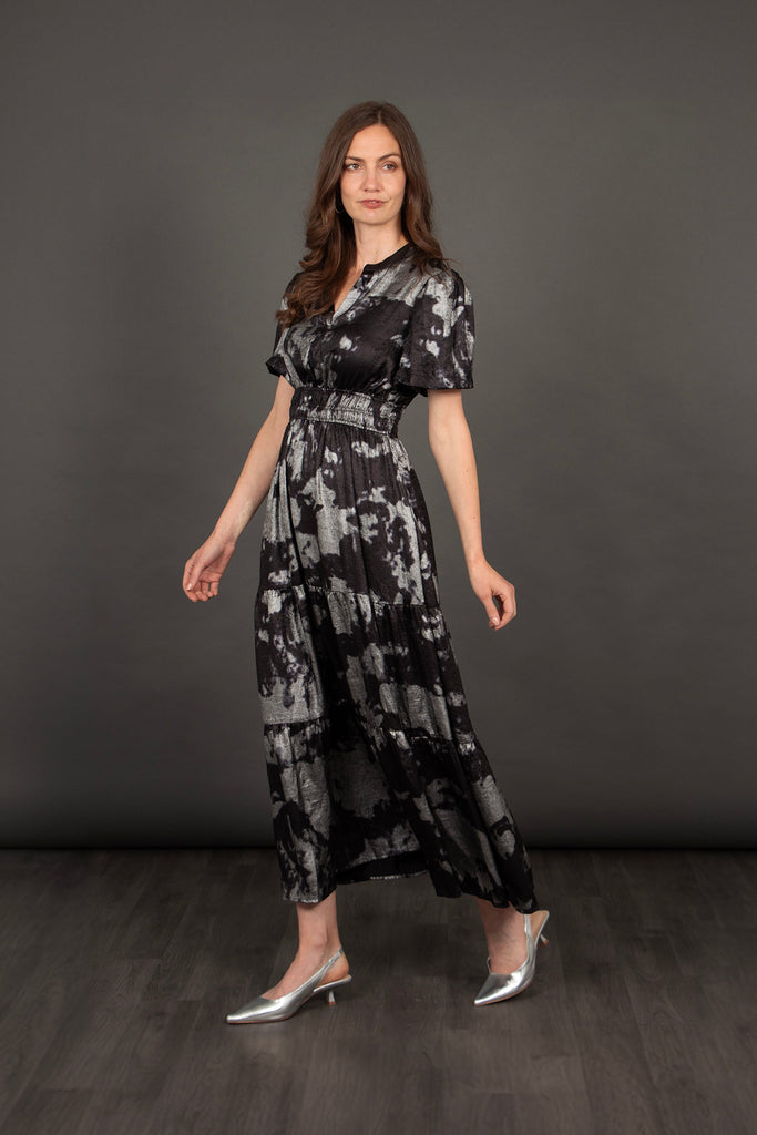 model showing the side view of the dress, the tiered skirt is loose fitting and sits just above the ankles