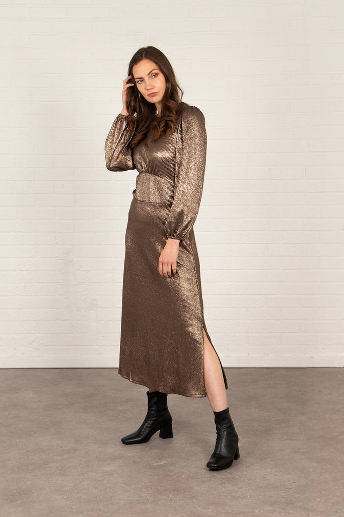 model showing the side splits on the side of the bronze long sleeved tea dress