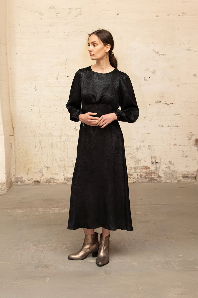 model wearing the black dress accessorised with gold boots.