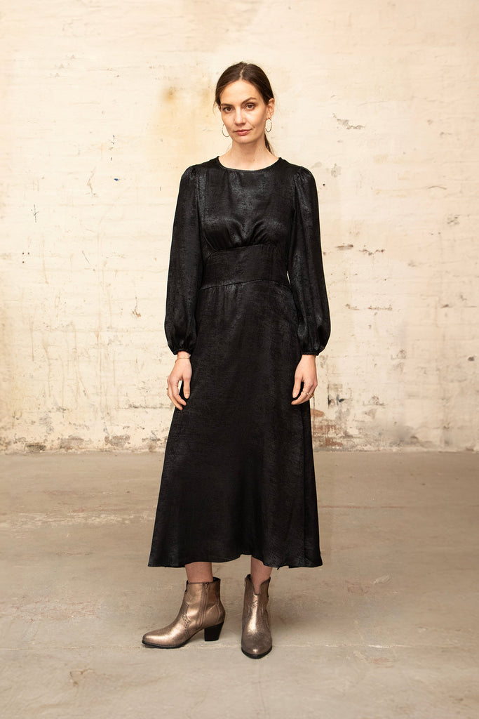 model wearing the black midi dress, the loose fitting balloon sleeves and panel bodice are visible 