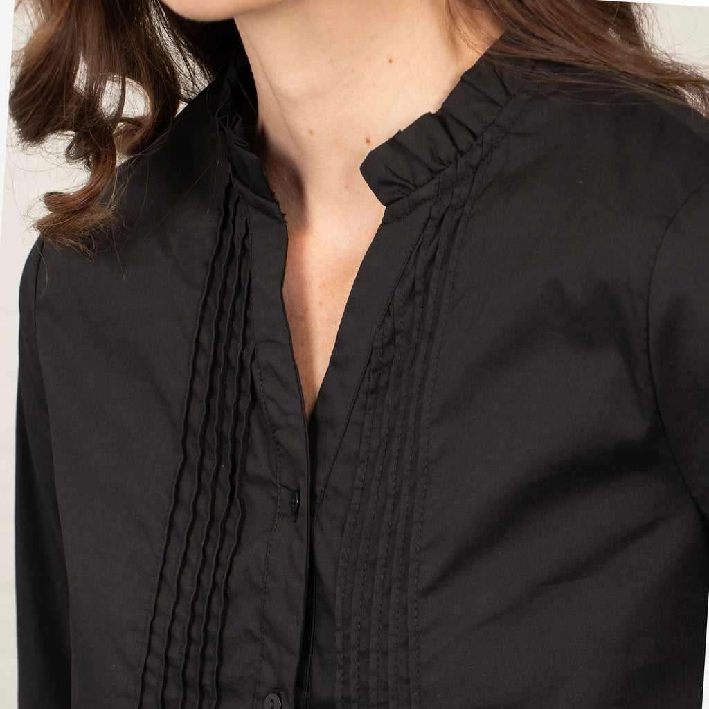 showing the pleated details on the front of the shirt and the open v-neck collar