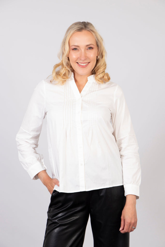 model wearing a slim fitting white cotton shirt, the shirt has pleats on the front and has button front closure