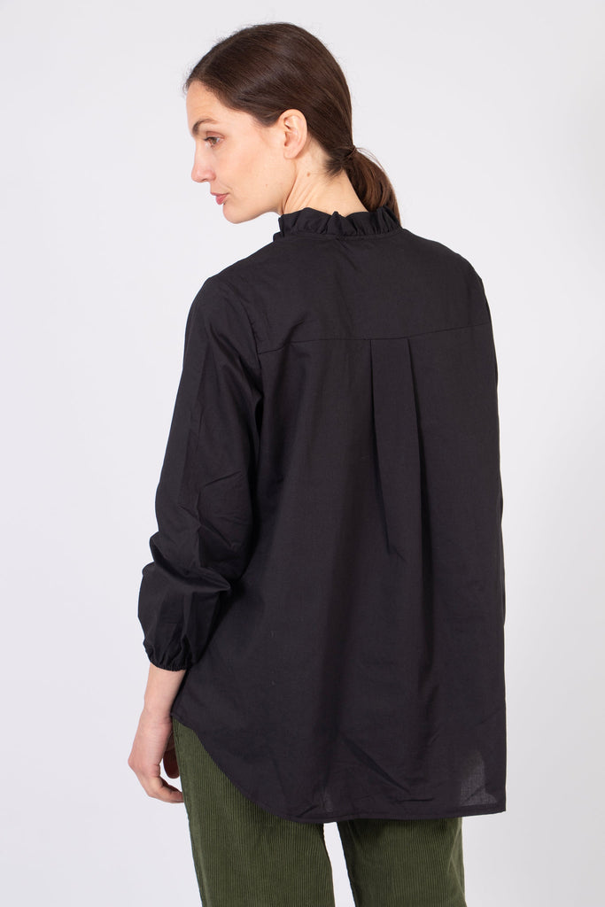 model showing the back of the shirt, highlighting the dipped hem feature. the shirt is longer at the back than the front