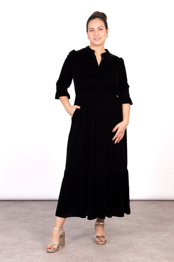 model wearing a black velvet maxi dress with v-neck and 3/4 fluted sleeves