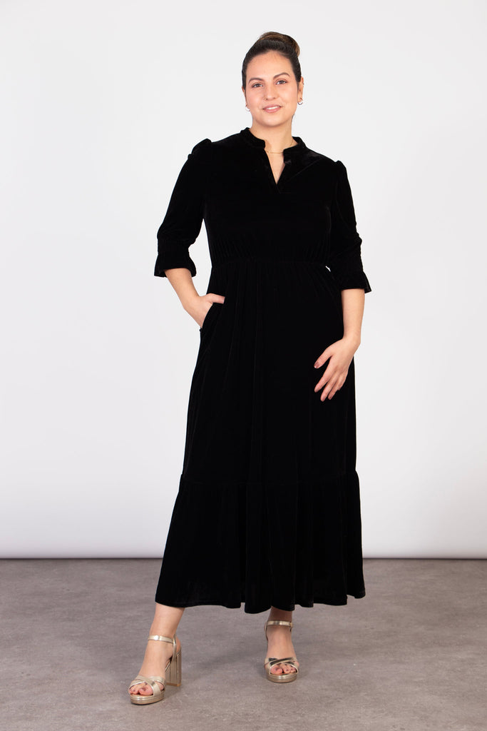 model wearing a black velvet maxi dress with v-neck and 3/4 fluted sleeves