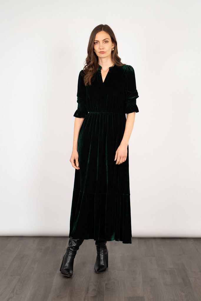 model wearing a midaxi length green velvet dress with fluted cropped sleeves and v-neck