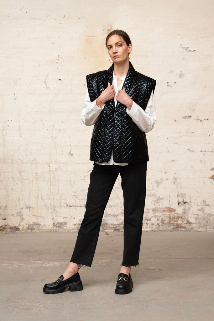 model wearing an open front shiny black quilted gilet