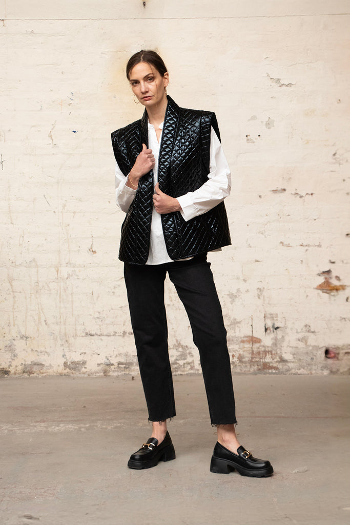 model wearing a black quilted body warmer over a white shirt, showing how it can be worn for layering