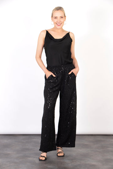 model wearing a pair of black sequin wide leg trousers with pockets at the front and an elasticated waist.