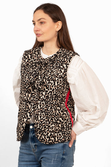 model wearing a natural animal print quilted gilet with front ties and a red striped which runs vertically down the side of the piece.