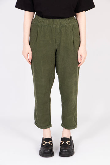 model wearing a pair of khaki green tapered babycord trousers with an elasticated waist