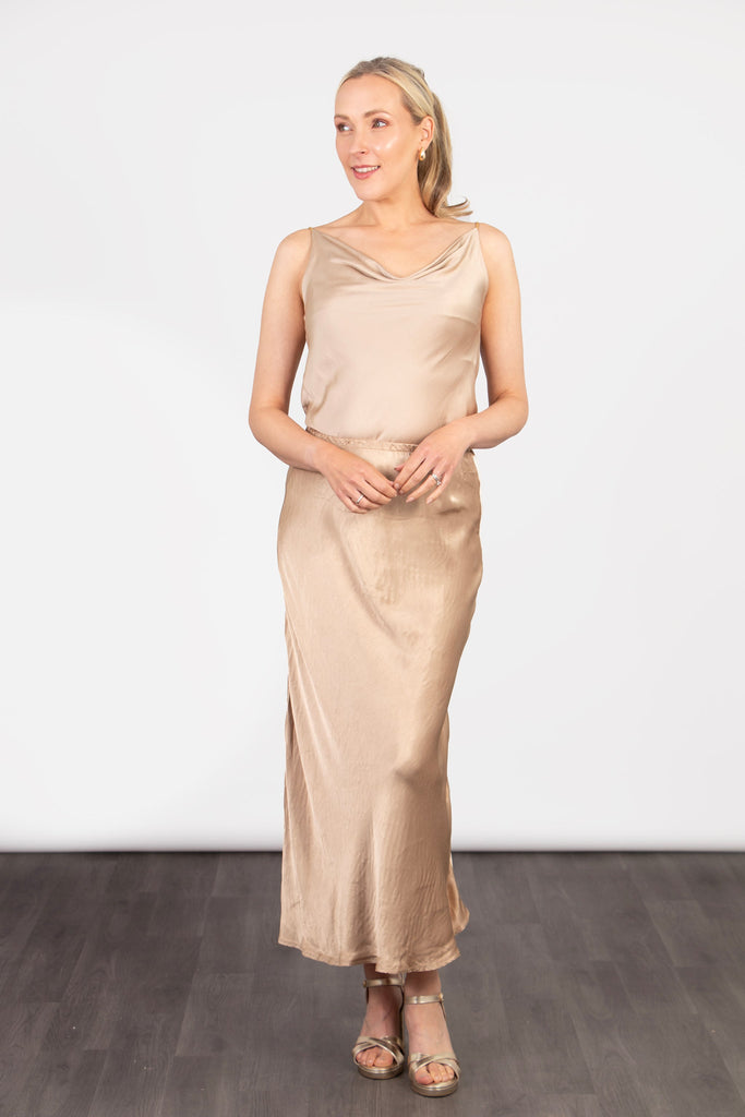 model wearing a midi length gold slip skirt with an elasticated waist