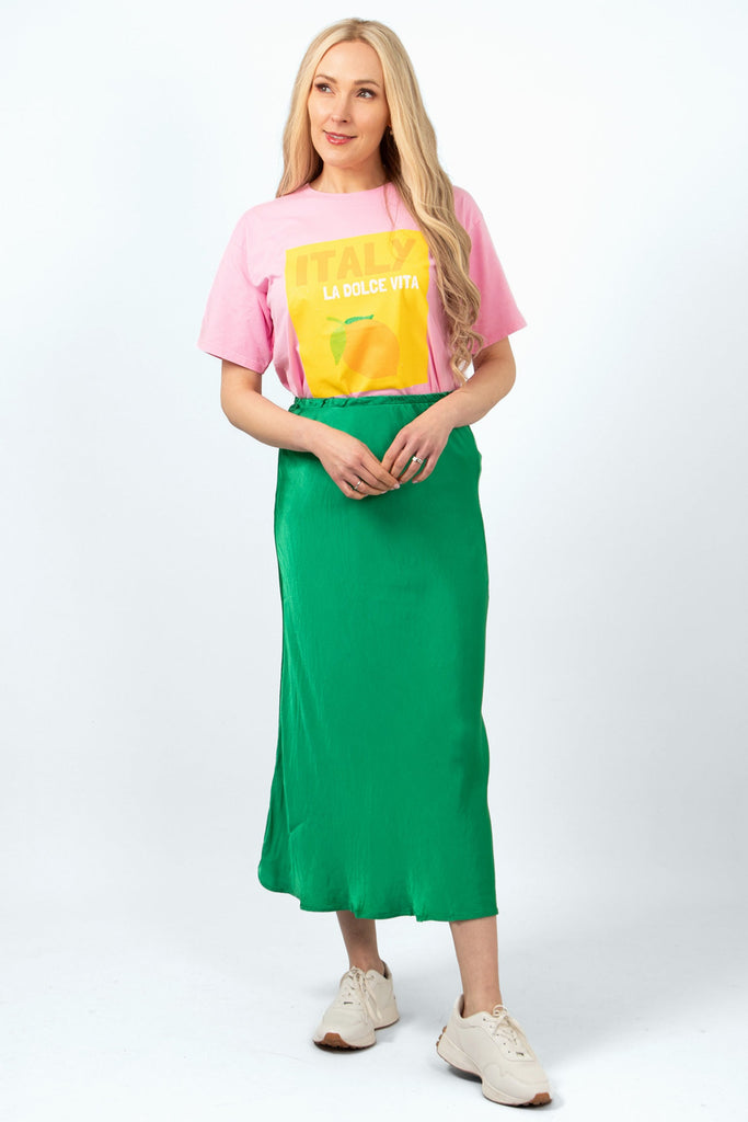 cassie-midi-slip-skirt-green-styled-on-model-pink-tshirt-trainers