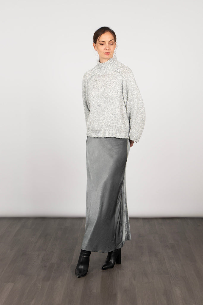 model wearing a silver pewter long slip skirt, paired with boots and a grey jumper to accessorise