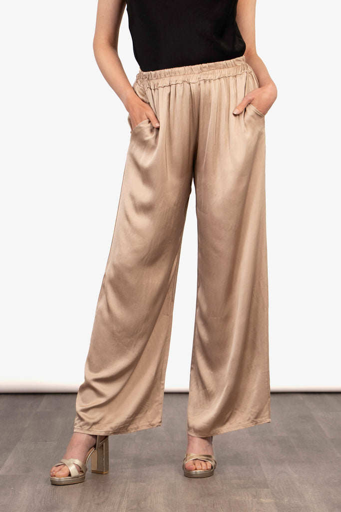 model wearing a pair of camel gold silky wide leg trousers