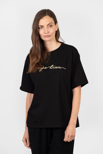 model wearing a black cotton t-shirt with the words, carpe diem, embroidered in gold on the front