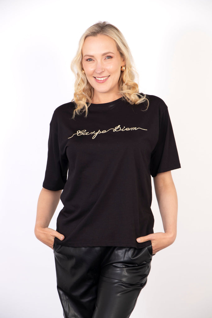 model wearing a black t-shirt with a gold embroidered slogan "carpe diem" on the front