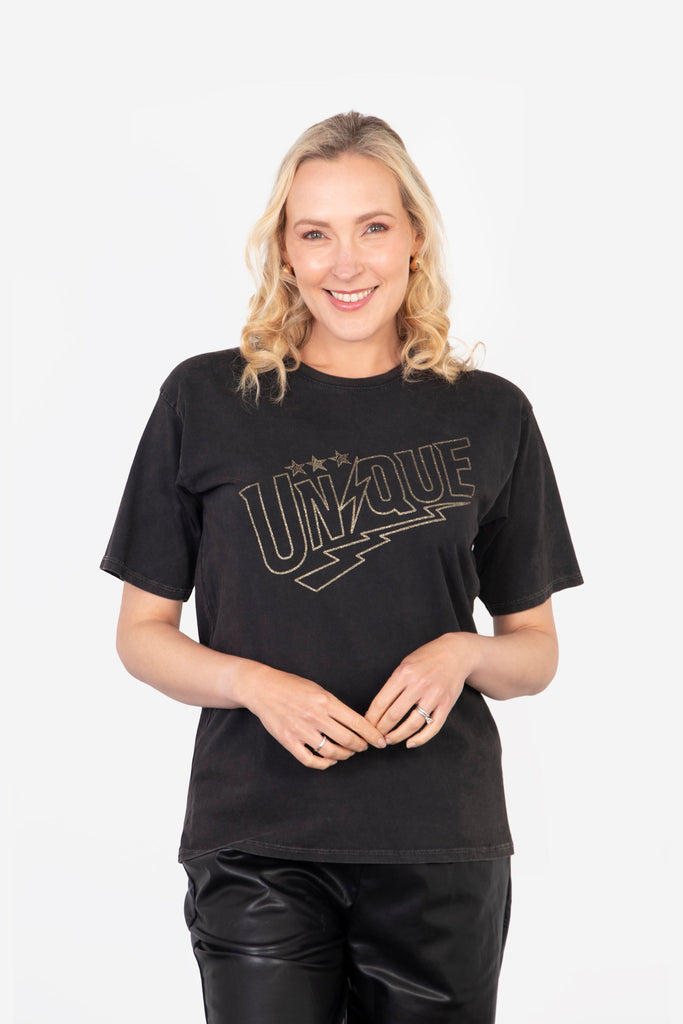 model wearing a black t-shirt with a gold embellished glitter slogan "unique" on the front