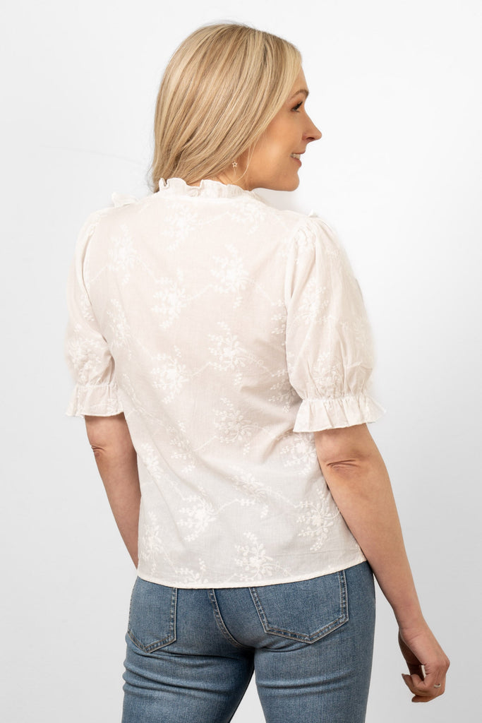 bronte-cotton-ruffle-shirt-white-floral-embroidery-on-model-front-view-frilly-trims-flower-pattern