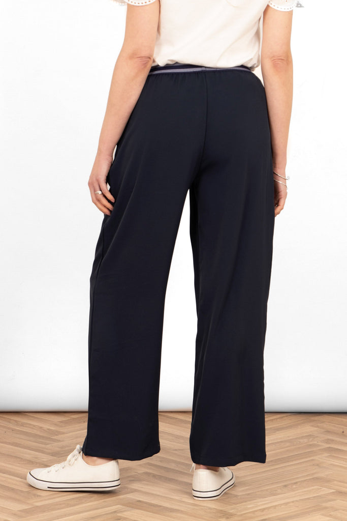 amber-wide-leg-trousers-navy-blue-model-showing-rear-view-the-trousers-are-full-length