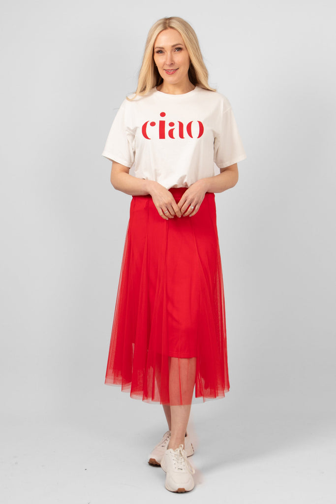 model wearing a white cotton t-shirt with the word ciao printed in red on the front. the t-shirt is styles with a red tulle midi skirt and white trainers.