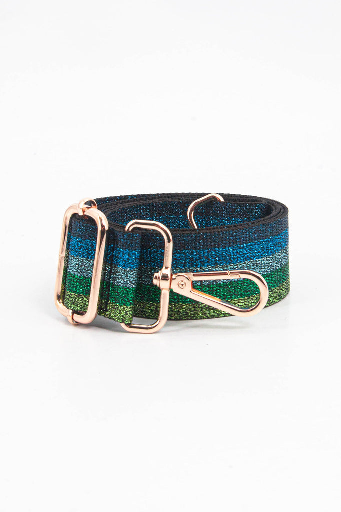 showing the bag strap coiled around itself, the blue and green glitter stripe design is prominent , the gold hardware is shown in close up