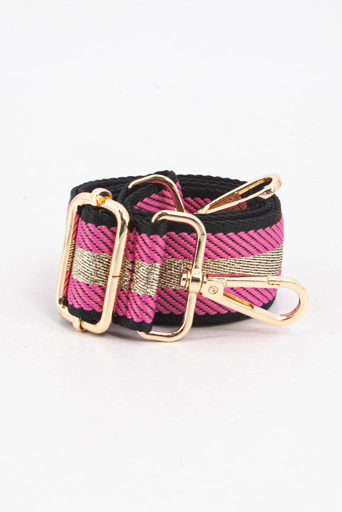 showing the bag strap coiled around itself, the fuchsia pink and gold glitter stripe pattern woven design is prominent , the gold hardware is shown in close up