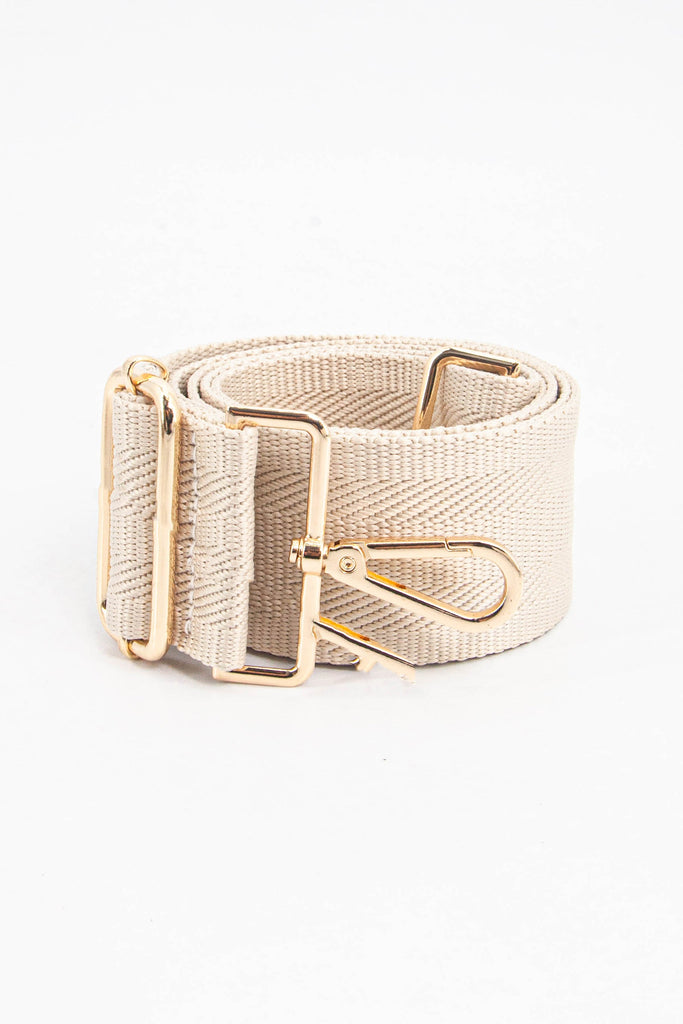 showing the bag strap coiled around itself, the plain cream woven design is prominent , the gold hardware is shown in close up