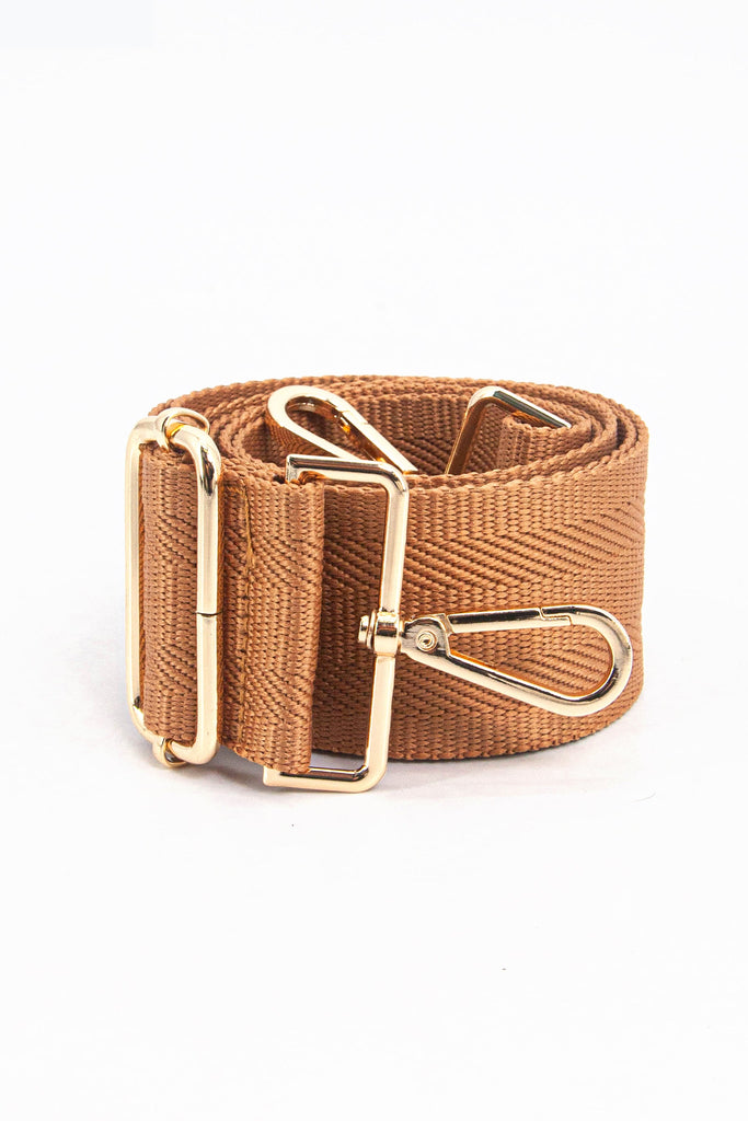 showing the bag strap coiled around itself, the tan brown woven design is prominent , the gold hardware is shown in close up