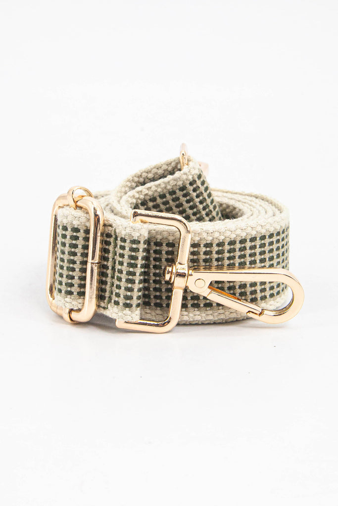 showing the bag strap coiled around itself, the khaki rattan woven design is prominent , the gold hardware is shown in close up