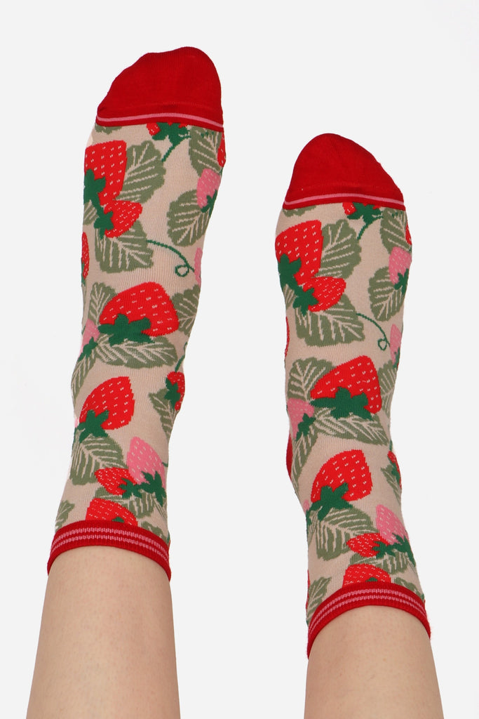 Ladies feet straight in the air wearing strawberry print fruit socks. Highlighting contrasting red toe detail