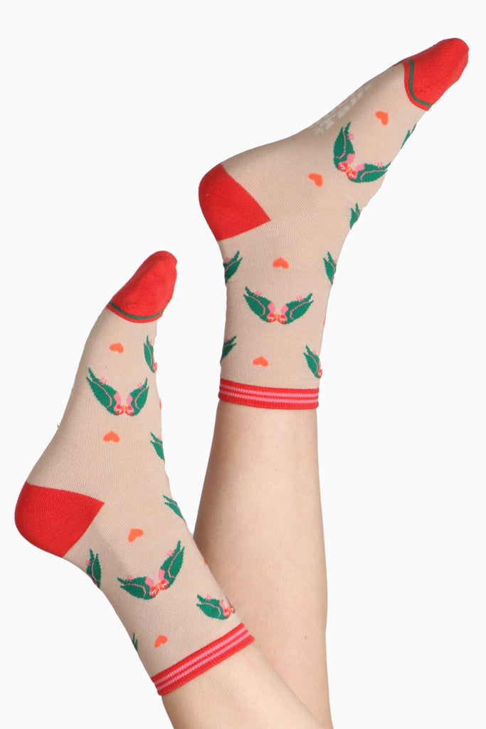 Ladies feet in air wearing bamboo socks. Sock are printed with lovebirds on a cream base with a coral pinkey tone contrasting toe and heel
