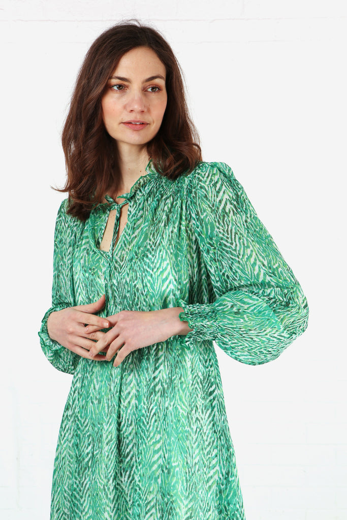 model wearing a green chevron print chiffon midi dress with shirring at the shoulders and cuffs