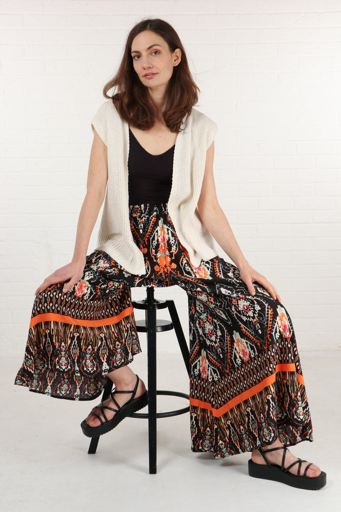 wide leg palazzo pants with an ornate black and orange mandala print pattern