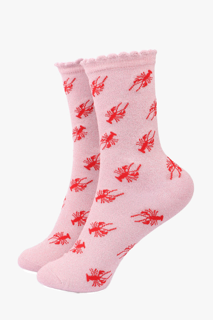 light pink socks with a red lobster parttern and an all over silver glitter sparkle, the socks have frilly scalloped cuffs