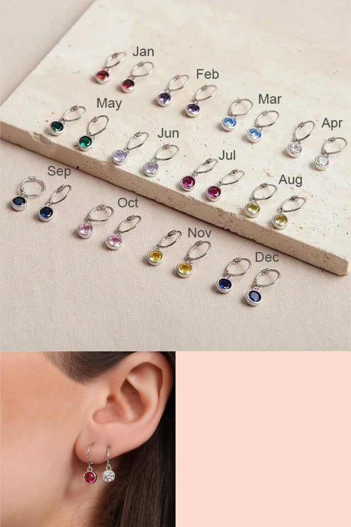 silver huggie hoop earrings with a round cz charm hanging below, each month of the year has a different colour