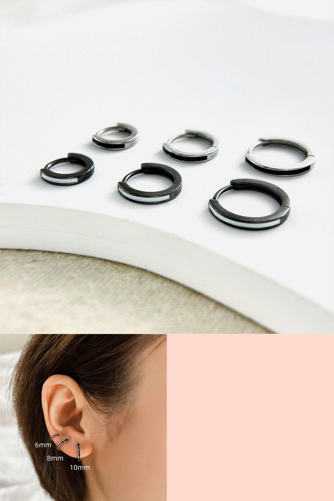 three sizes of black and silver huggie hoop earrings made from pure s999 sterling silver, the hoops come in black and white and silver with black details in sizes 6mm, 8mm and 10mm