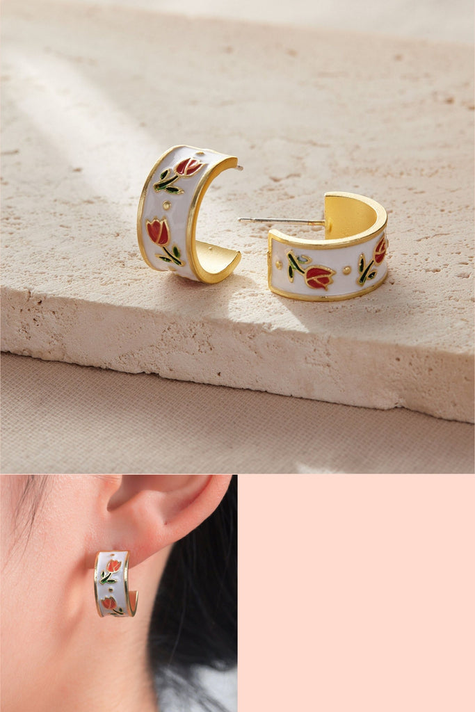 white enamel half hoop earrings with pink tulip flowers on them, the earrings are made from copper and have sterling silver pins and butterfly backs