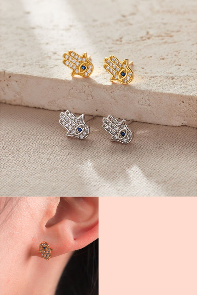 sterling silver sparkly hamsa hand stud earrings in silver and gold, clear cz with a blue eye in the middle of the palm