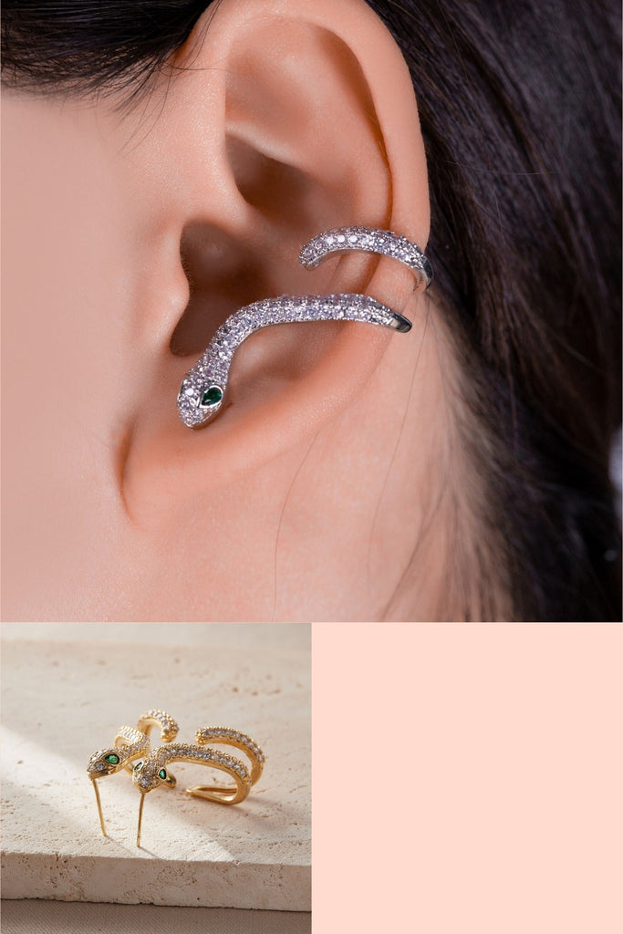 model wearing a silver sparkly snake climber earring, the earring is fastened through the earlobe by a butterfly back and winds around the ear cuff. the snake is encrusted with many white cz crystals with two large green crystals for the eyes, this style is available in silver and gold colourways