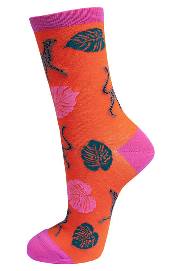 vibrant orange socks with a pink heel, toe and cuff with an all over pattern of cheetah cats and large tropical leaves