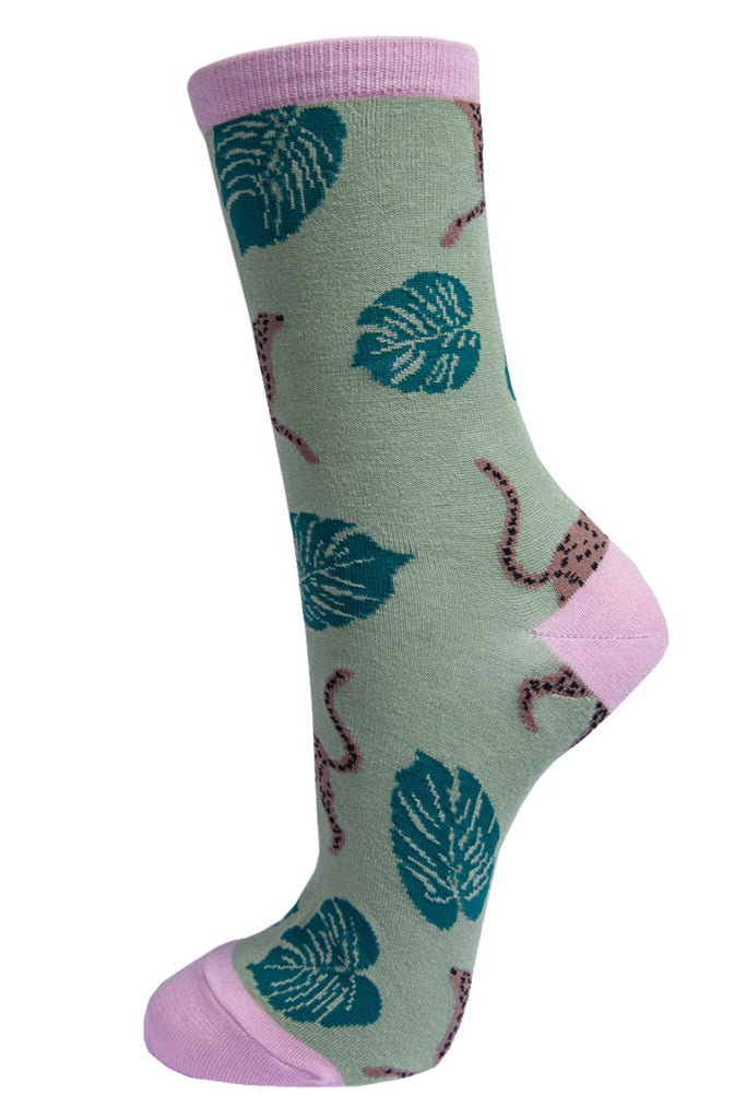 light green socks with a pink heel, toe and cuff with an all over pattern of cheetah cats and large tropical leaves