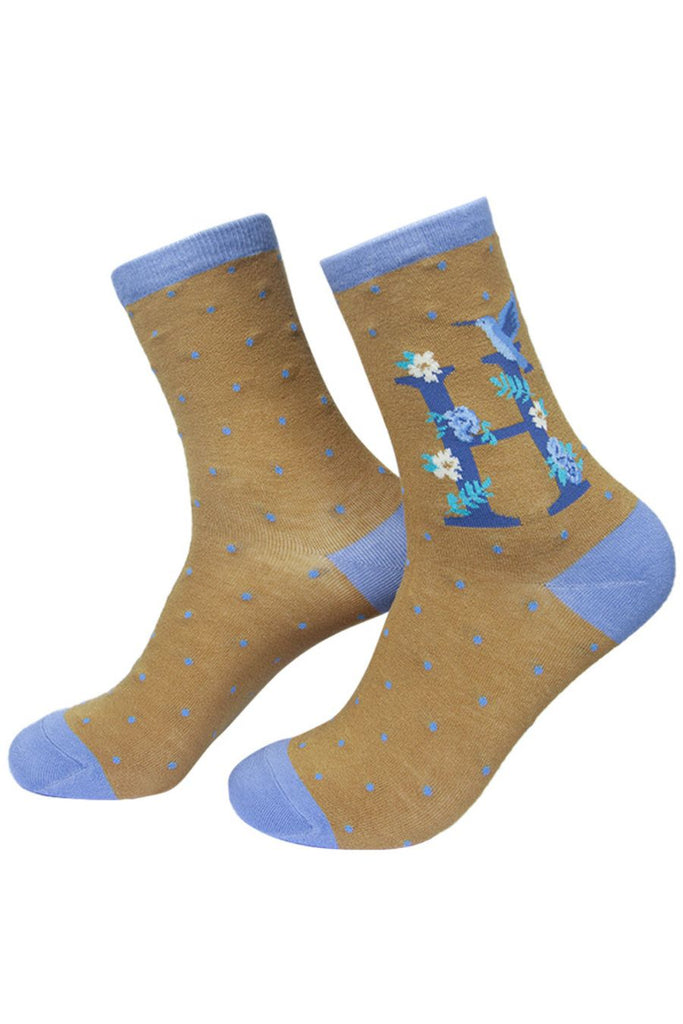 mustard yellow and blue socks with a large letter h, a hummingbird and a floral pattern on the ankle