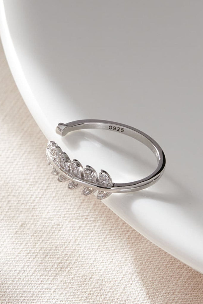 laying flat, the silver coloured S925 ring, showing the clear cz stones of the leaf part of the ring