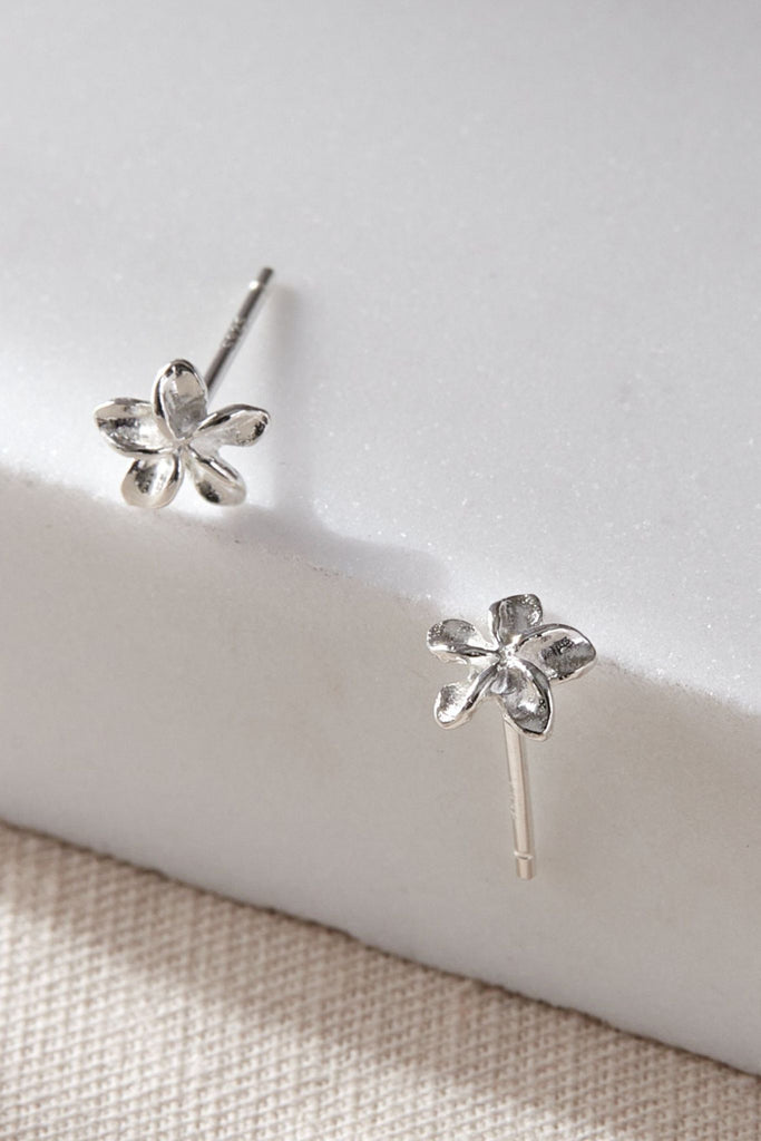 close up of the earrings, showing the stems and the dainty five petal floral design