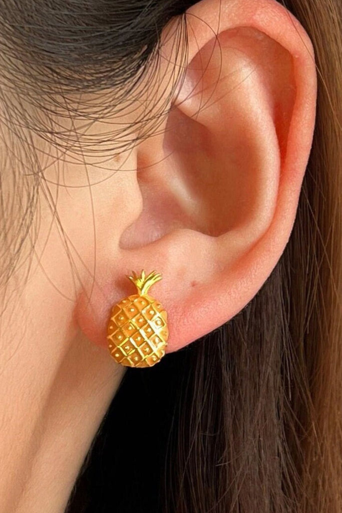 pineapple stud earrings being worn on the earlobe