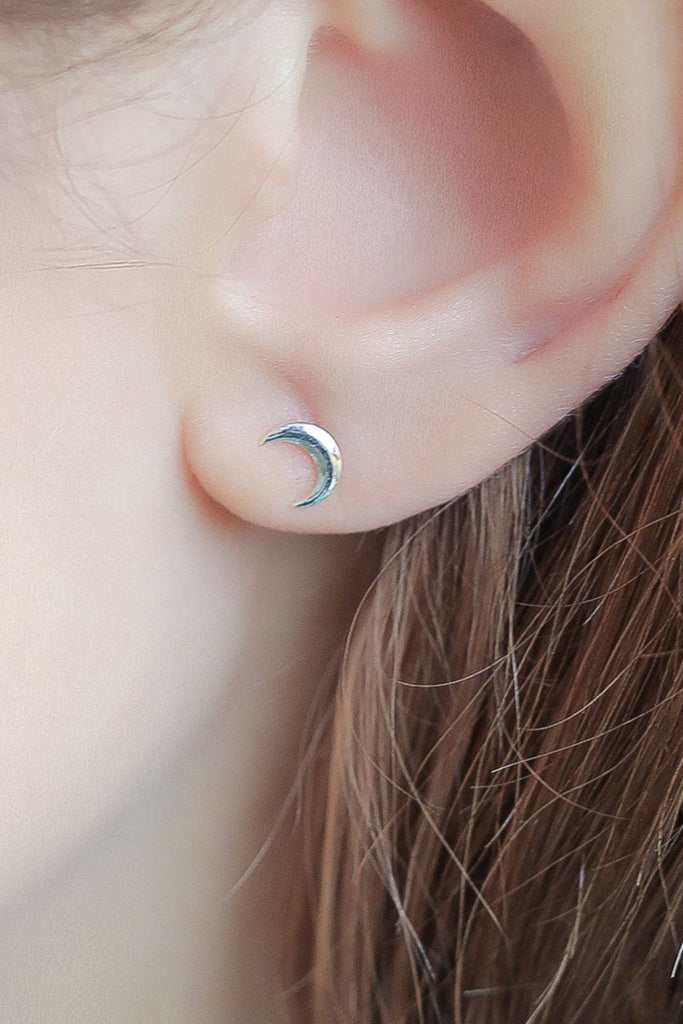sterling silver crescent moon stud earring being worn on the earlobe