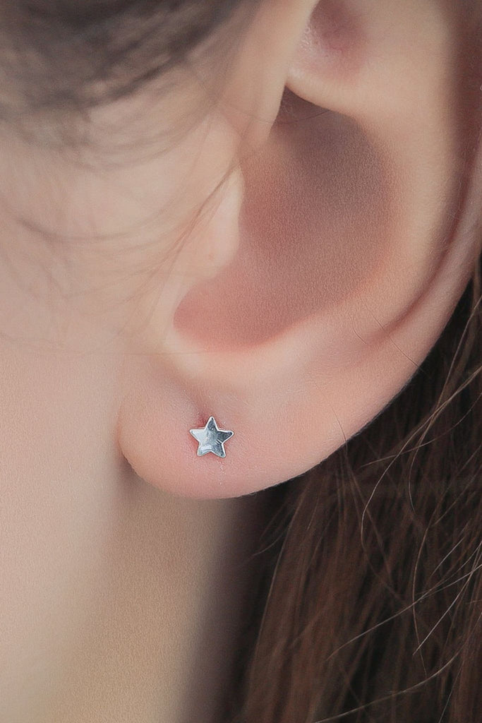 dainty minimalist star stud earrings being worn in the earlobe
