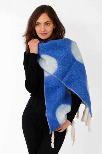 model wearing a blue winter scarf with a large spot pattern and white tassles