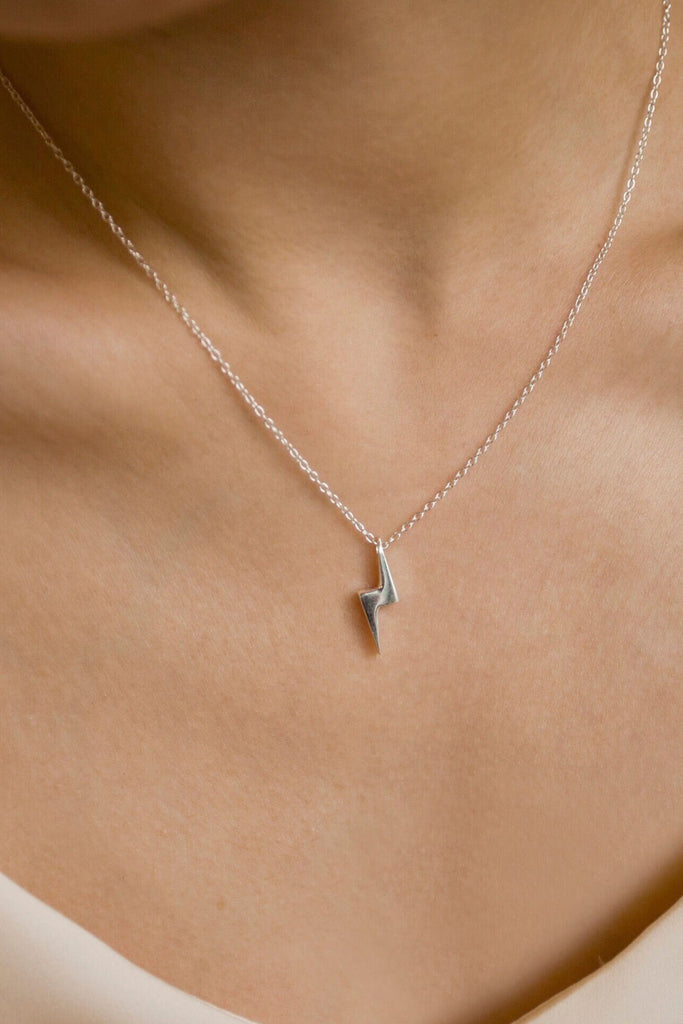 model wearing a silver lightning bolt pendant necklace around the neck